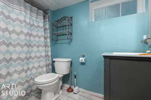 Bathroom featuring vanity, a textured ceiling, tile patterned floors, a shower with curtain, and toilet