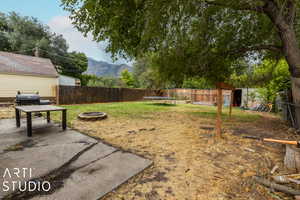 View of yard featuring a trampoline, a mountain view, an outdoor fire pit, and a patio area