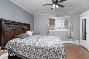 Bedroom with a textured ceiling, cooling unit, ceiling fan, hardwood / wood-style flooring, and ornamental molding