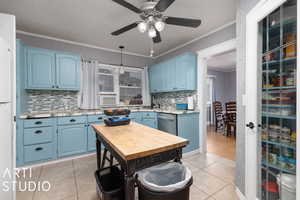 Kitchen with stainless steel dishwasher, ornamental molding, ceiling fan, and blue cabinetry