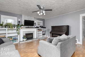 Living room with a textured ceiling, a tiled fireplace, ceiling fan, and hardwood / wood-style flooring