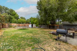 View of yard with a trampoline and a storage unit