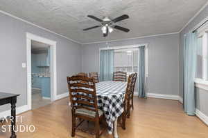 Dining space with wood walls, light hardwood / wood-style floors, ornamental molding, and ceiling fan