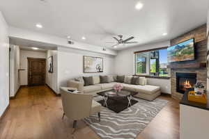 Living room featuring ceiling fan, a fireplace, and light wood-type flooring