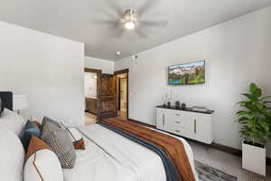 Bedroom featuring ceiling fan, light colored carpet, and ensuite bath