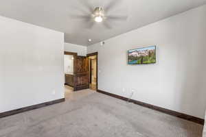 Unfurnished bedroom with connected bathroom, light carpet, and ceiling fan