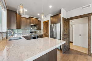 Kitchen with pendant lighting, sink, dark wood-type flooring, and stainless steel appliances