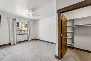 Unfurnished bedroom featuring ceiling fan, a closet, and light carpet