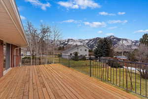 Wooden deck featuring a mountain view and a lawn