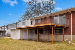 Rear view of house with a yard and a wooden deck