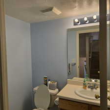 Bathroom with vanity, toilet, and a textured ceiling