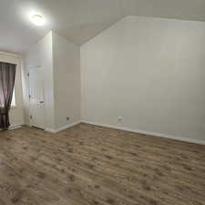 Empty room featuring lofted ceiling and dark wood-type flooring