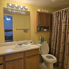 Bathroom with ceiling fan, vanity, toilet, and a textured ceiling