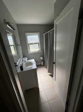 Bathroom featuring curtained shower, vanity, tile patterned flooring, and a wealth of natural light