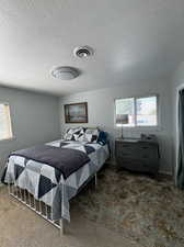 Carpeted bedroom featuring multiple windows and a textured ceiling