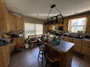 Kitchen with sink, tasteful backsplash, a kitchen island, decorative light fixtures, and appliances with stainless steel finishes