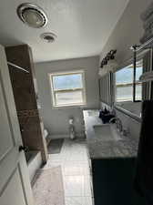 Full bathroom featuring tiled shower / bath, vanity, toilet, and a wealth of natural light