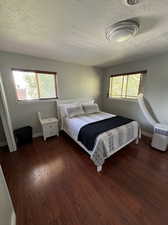 Bedroom featuring multiple windows, dark wood-type flooring, and a textured ceiling