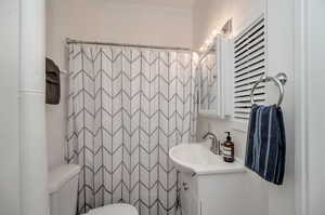 Bathroom featuring vanity, tile walls, toilet, and curtained shower