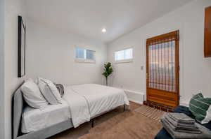 Bedroom with lofted ceiling and dark colored carpet