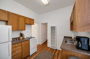 Kitchen with white appliances, dark hardwood / wood-style floors, and sink