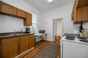 Kitchen with white electric stove, dark hardwood / wood-style floors, and sink