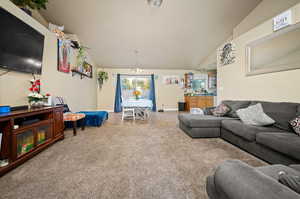 Carpeted living room with vaulted ceiling and a chandelier