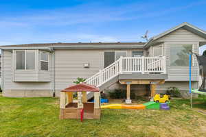 Back of house featuring a wooden deck, a yard, and a trampoline