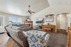 Tiled living room featuring ceiling fan and vaulted ceiling