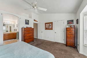 Primary Bedroom with ceiling fan, light carpet, ensuite bathroom, walk-in closet and vaulted ceiling