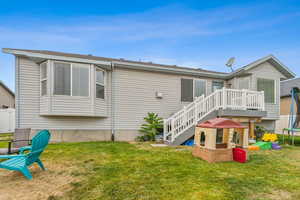 Rear view of property featuring a trampoline, a lawn, and a deck