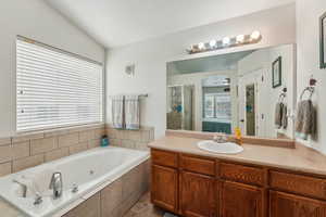 Primary Bathroom featuring vanity, lofted ceiling, tile patterned flooring, and shower with separate bathtub