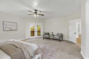 Primary Bedroom with access to outside, ceiling fan, light colored carpet, and french doors