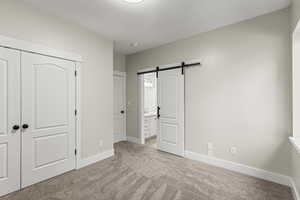 Bedroom #4  featuring light carpet, a closet, and a barn door