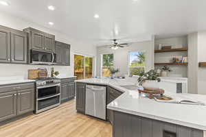 Kitchen featuring light stone counters, light hardwood / wood-style flooring, stainless steel appliances, and gray cabinetry