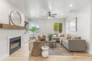 Living room with a textured ceiling, light hardwood / wood-style floors, and ceiling fan