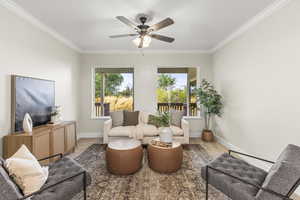 Carpeted living room featuring crown molding and ceiling fan