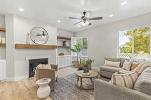 Living room featuring light wood-type flooring, ceiling fan, and a wealth of natural light