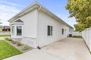 View of side of property featuring central AC unit, a lawn, and a patio area