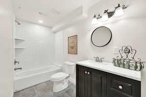 Full bathroom with tile patterned floors, vanity, tiled shower / bath combo, and toilet