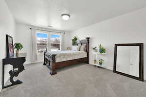 Bedroom featuring light colored carpet and a textured ceiling