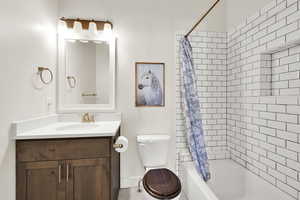 Full bathroom with vanity, shower / bath combination with curtain, and toilet