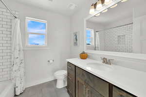 Full bathroom featuring vanity, toilet, and shower / bathtub combination with curtain