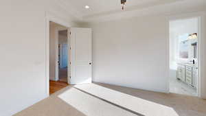 Unfurnished bedroom featuring ensuite bathroom, light colored carpet, and sink