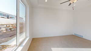 Unfurnished room featuring light carpet, a tray ceiling, and ceiling fan