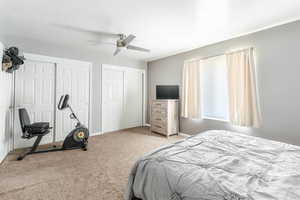 Carpeted bedroom featuring a textured ceiling, two closets, and ceiling fan