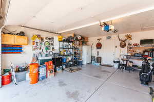 Garage featuring a garage door opener, a workshop area, and white fridge