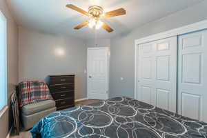 Carpeted bedroom featuring a closet, ceiling fan, multiple windows, and a textured ceiling