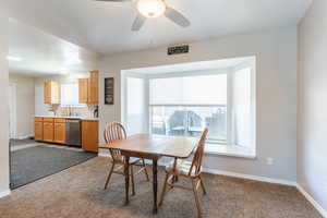 Dining space with ceiling fan, sink, carpet, and a wealth of natural light