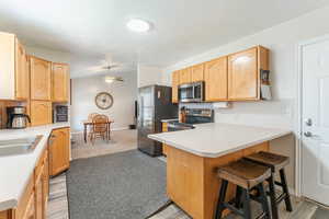 Kitchen with a breakfast bar, a textured ceiling, kitchen peninsula, appliances with stainless steel finishes, and ceiling fan